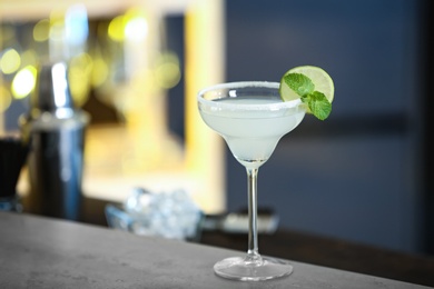 Fresh alcoholic cocktail with lime and mint on bar counter, space for text