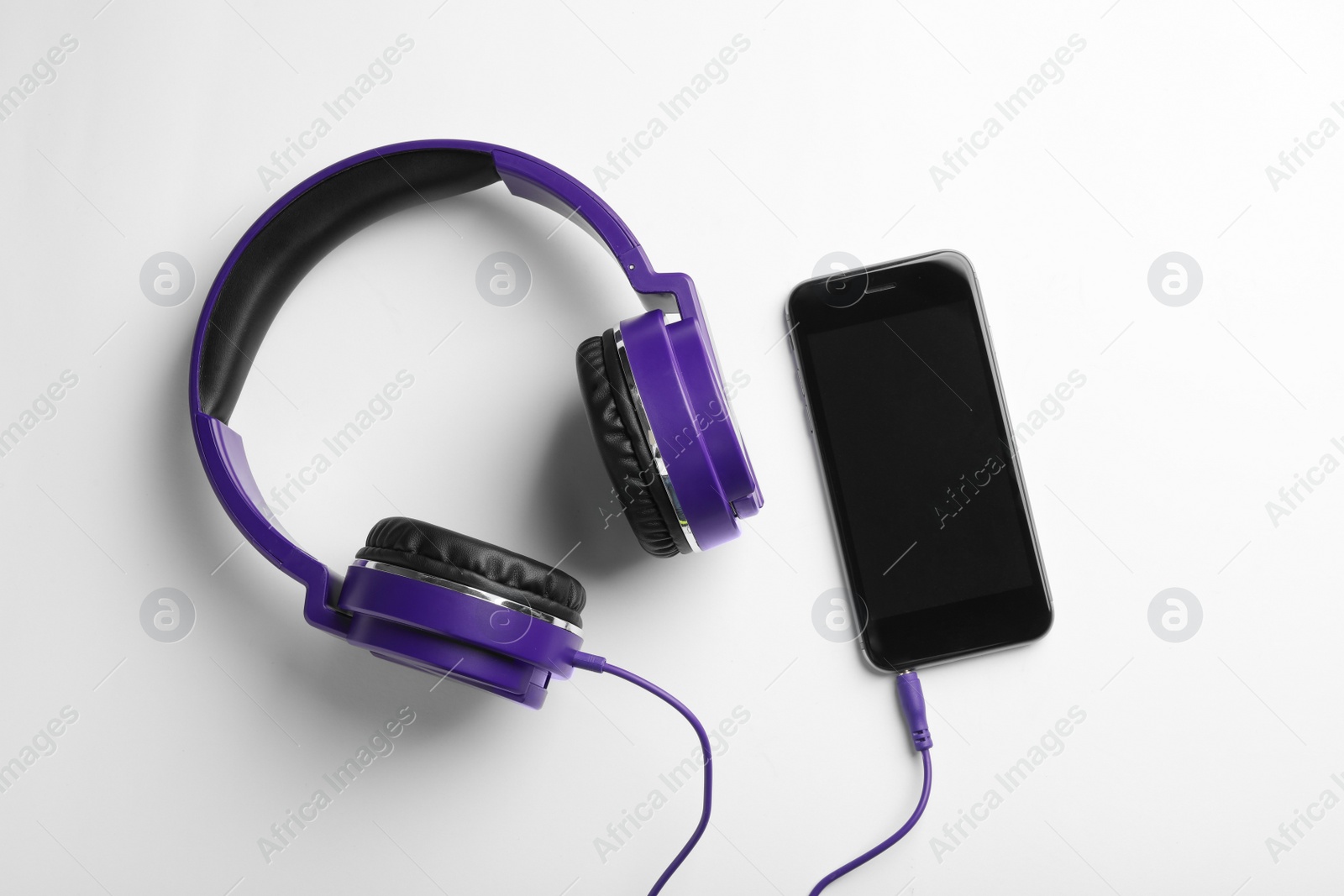 Photo of Stylish headphones and modern phone on white background, top view. Space for text