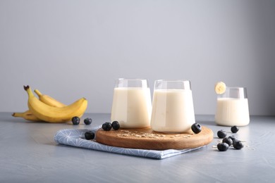 Photo of Tasty yogurt in glasses, oats and blueberries on grey table