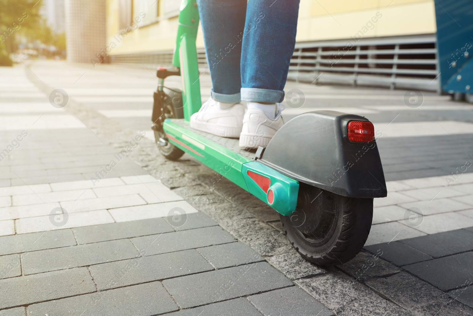 Photo of Woman riding modern electric kick scooter outdoors, closeup