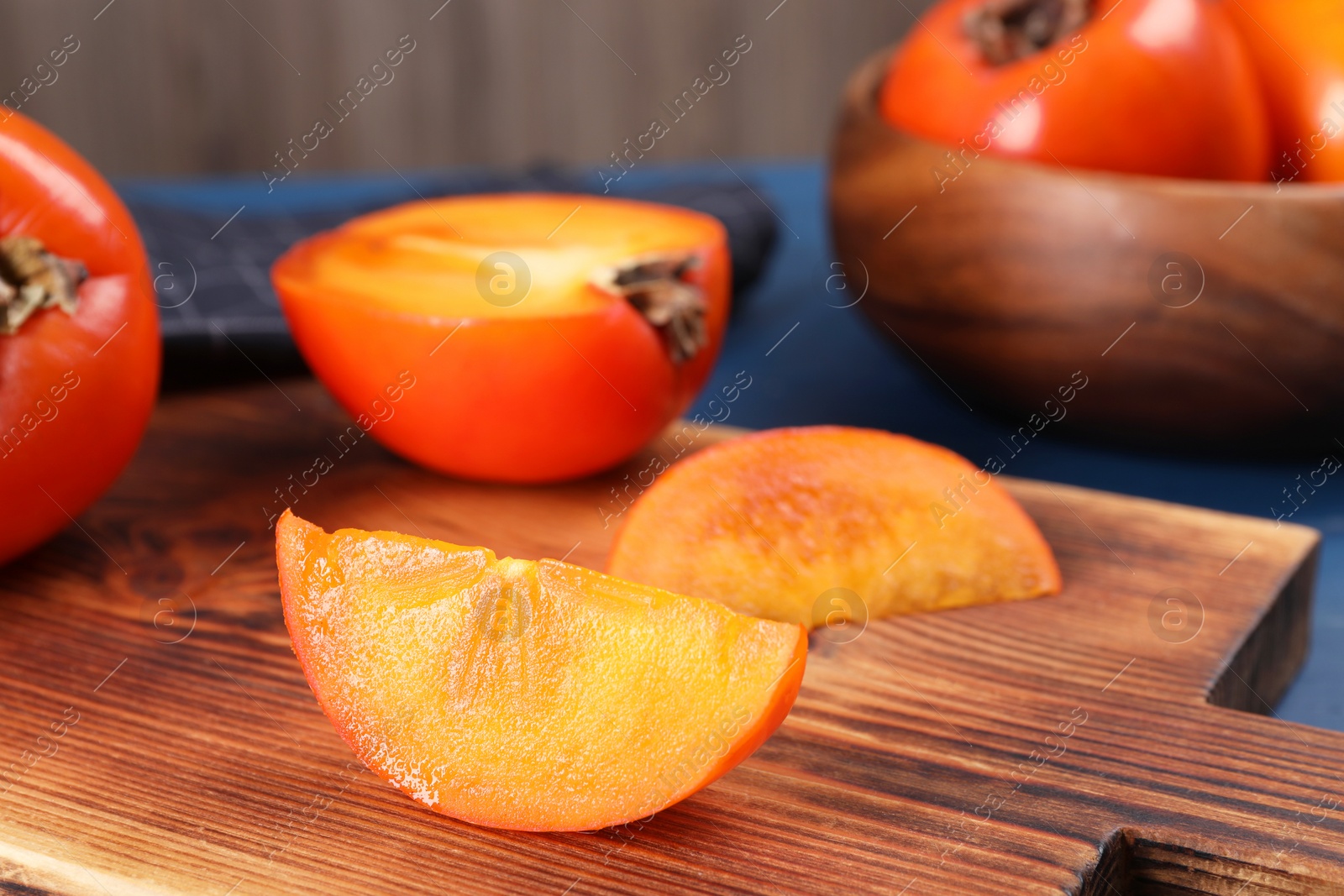 Photo of Delicious cut persimmon on wooden board, closeup