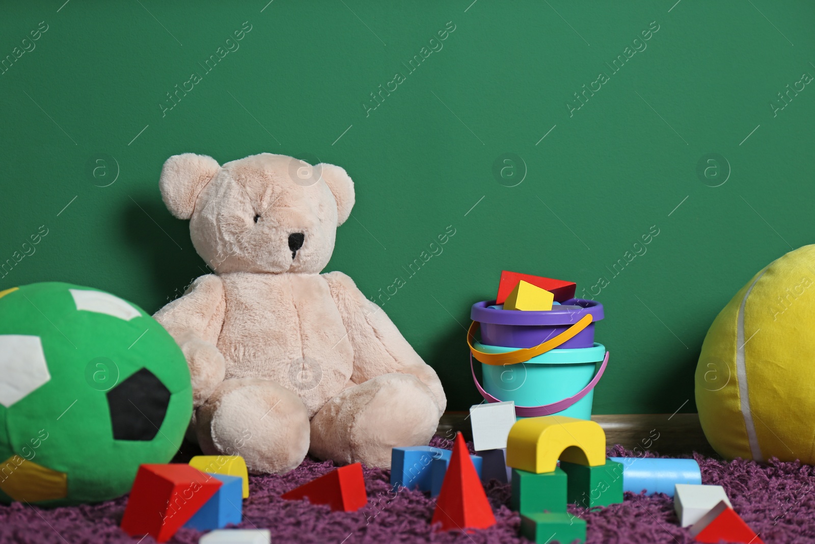 Photo of Set of different child toys on floor against color wall