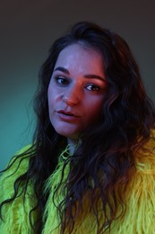 Portrait of beautiful woman in yellow fur coat on dark background with neon lights