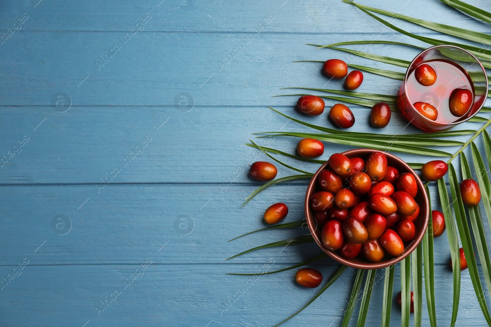 Photo of Palm fruits and oil on blue wooden table, flat lay. Space for text