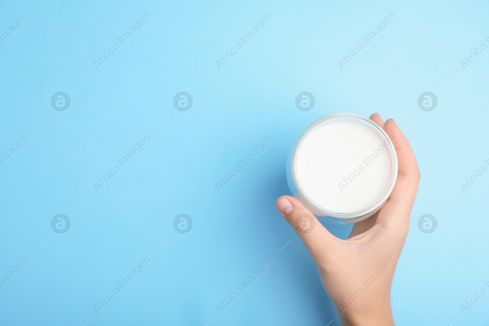 Photo of Woman holding glass of milk on color background, top view. Space for text