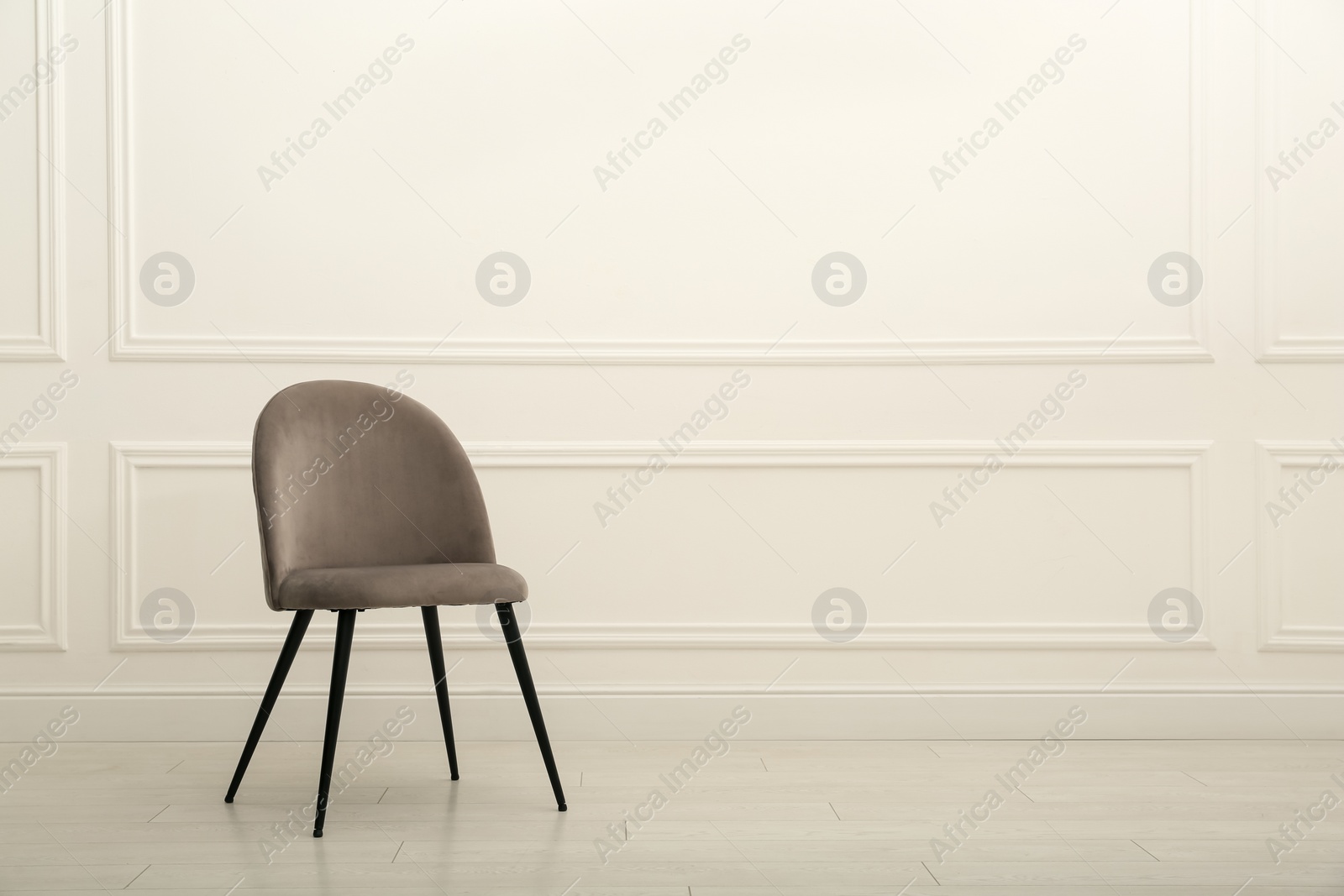 Photo of Modern beige chair near white wall indoors. Space for text