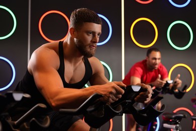 Young men training on exercise bikes in fitness club