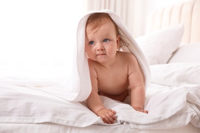 Cute little baby with soft towel on bed after bath