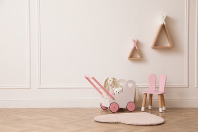 Photo of Child's toys, chair and wigwam shaped shelves on white wall indoors. Interior design