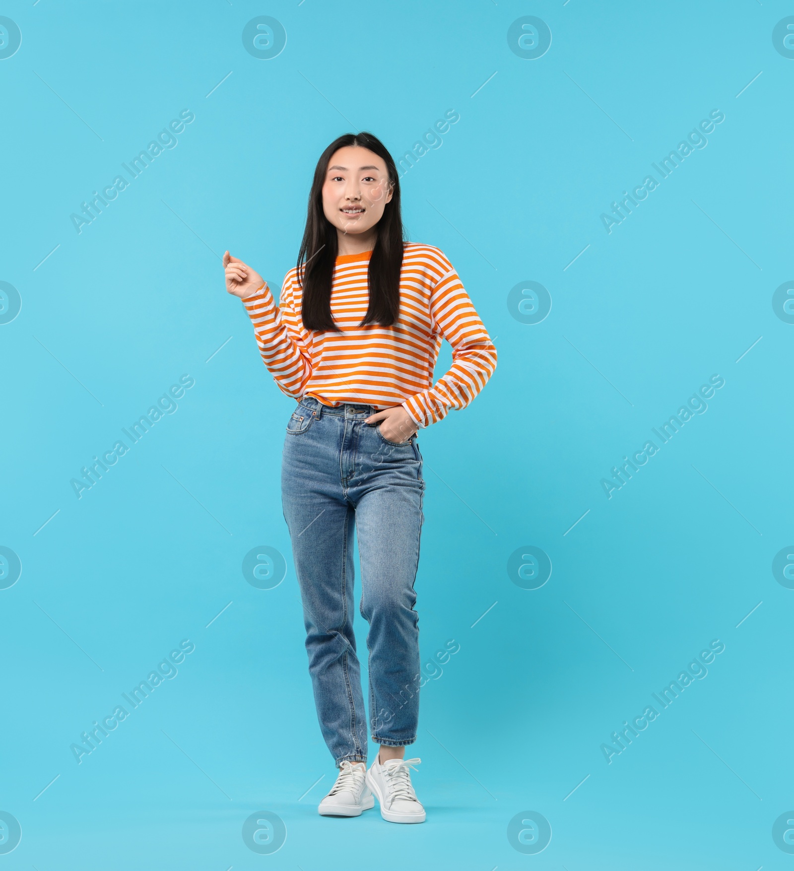 Photo of Full length portrait of smiling woman on light blue background