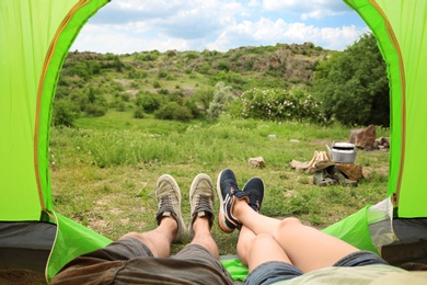 Photo of Young couple resting in camping tent, view from inside