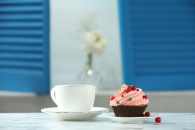 Photo of Delicious cupcake with pink cream and tea on white table