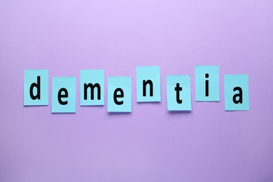 Photo of Word Dementia made of paper notes on violet background, flat lay