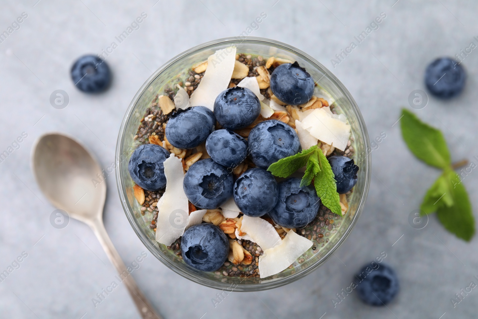 Photo of Tasty oatmeal with smoothie, blueberries, coconut and mint on grey table, flat lay. Healthy breakfast