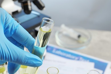 Doctor holding test tube with urine sample for analysis in laboratory, closeup. Space for text