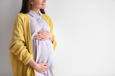 Photo of Young pregnant woman in casual clothes on light background