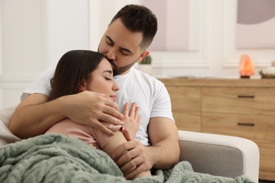 Photo of Affectionate young couple spending time together on sofa in living room. Space for text