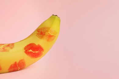 Photo of Banana covered with red lipstick marks on light pink background, space for text. Potency concept