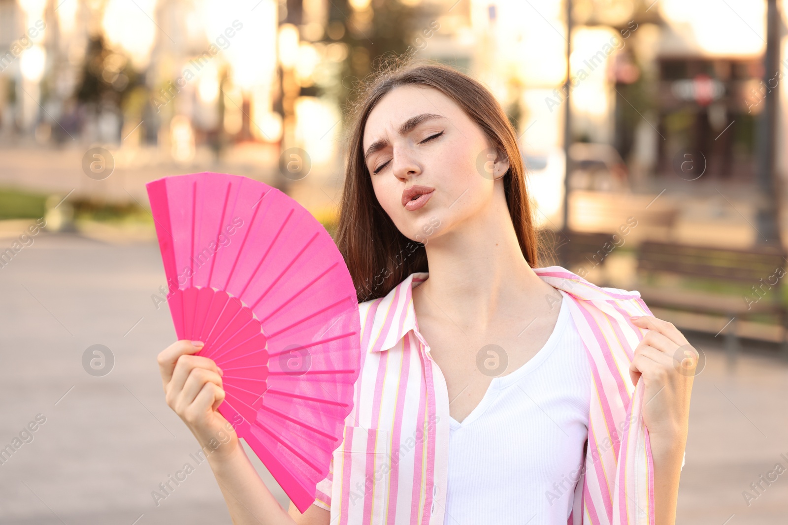 Photo of Woman with hand fan suffering from heat outdoors