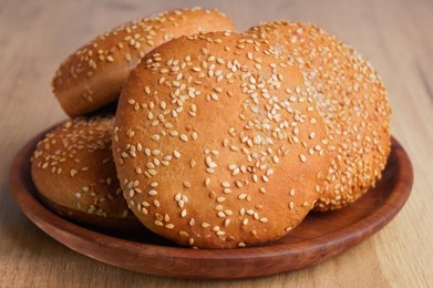 Photo of Fresh buns with sesame seeds on wooden table, closeup