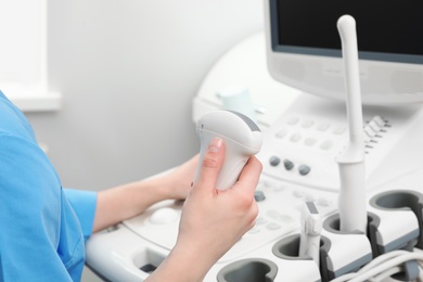 Photo of Sonographer operating modern ultrasound machine in clinic, closeup