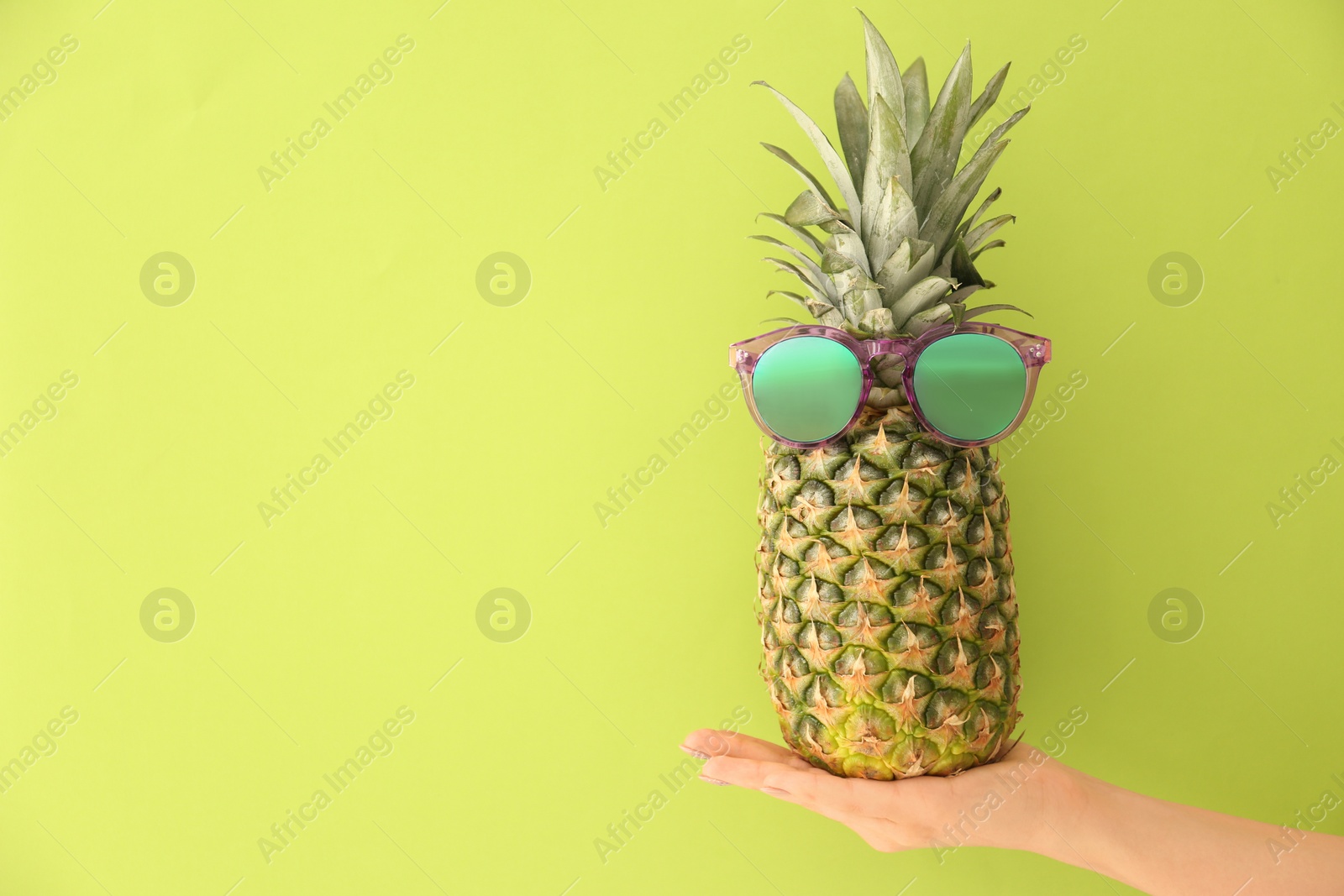 Photo of Woman holding fresh ripe pineapple with sunglasses on color background