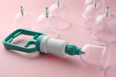 Photo of Plastic cups and hand pump on pink background. Cupping therapy