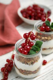 Photo of Delicious yogurt parfait with fresh red currants and mint on white wooden table, closeup