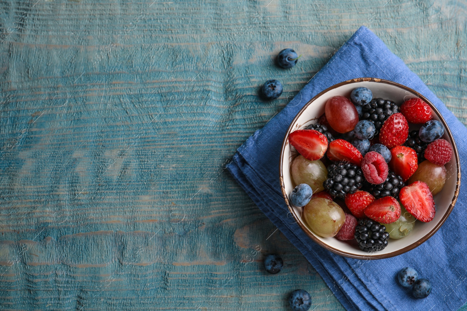 Photo of Fresh tasty fruit salad on blue wooden table, flat lay. Space for text