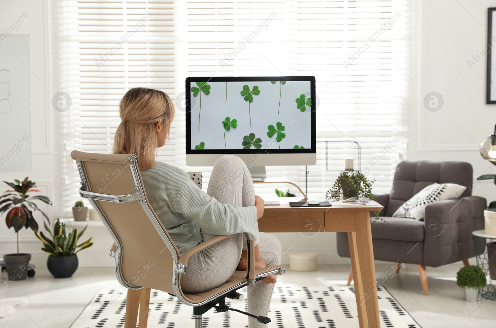 Photo of Woman with cup of tea at table in light room. Home office