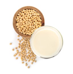 Glass of fresh soy milk and bowl with beans on white background, top view