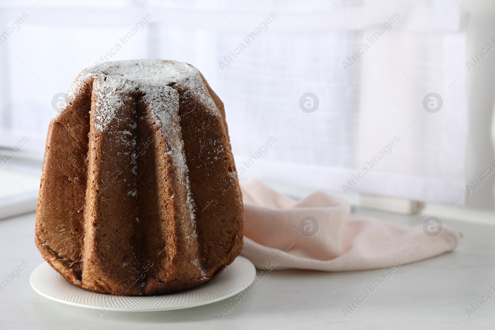 Photo of Delicious Pandoro cake decorated with powdered sugar on white table, space for text. Traditional Italian pastry