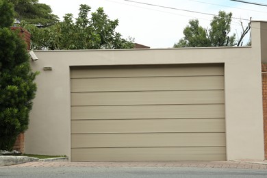 Photo of Beige garage with closed sectional door. Exterior design