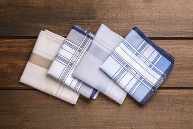 Photo of Different handkerchiefs folded on wooden table, flat lay