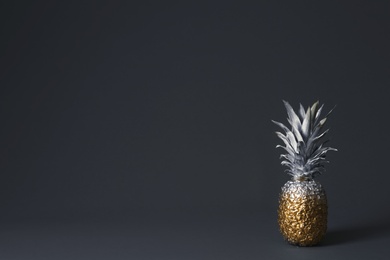 Pineapple painted with silver and gold on dark background. Space for text