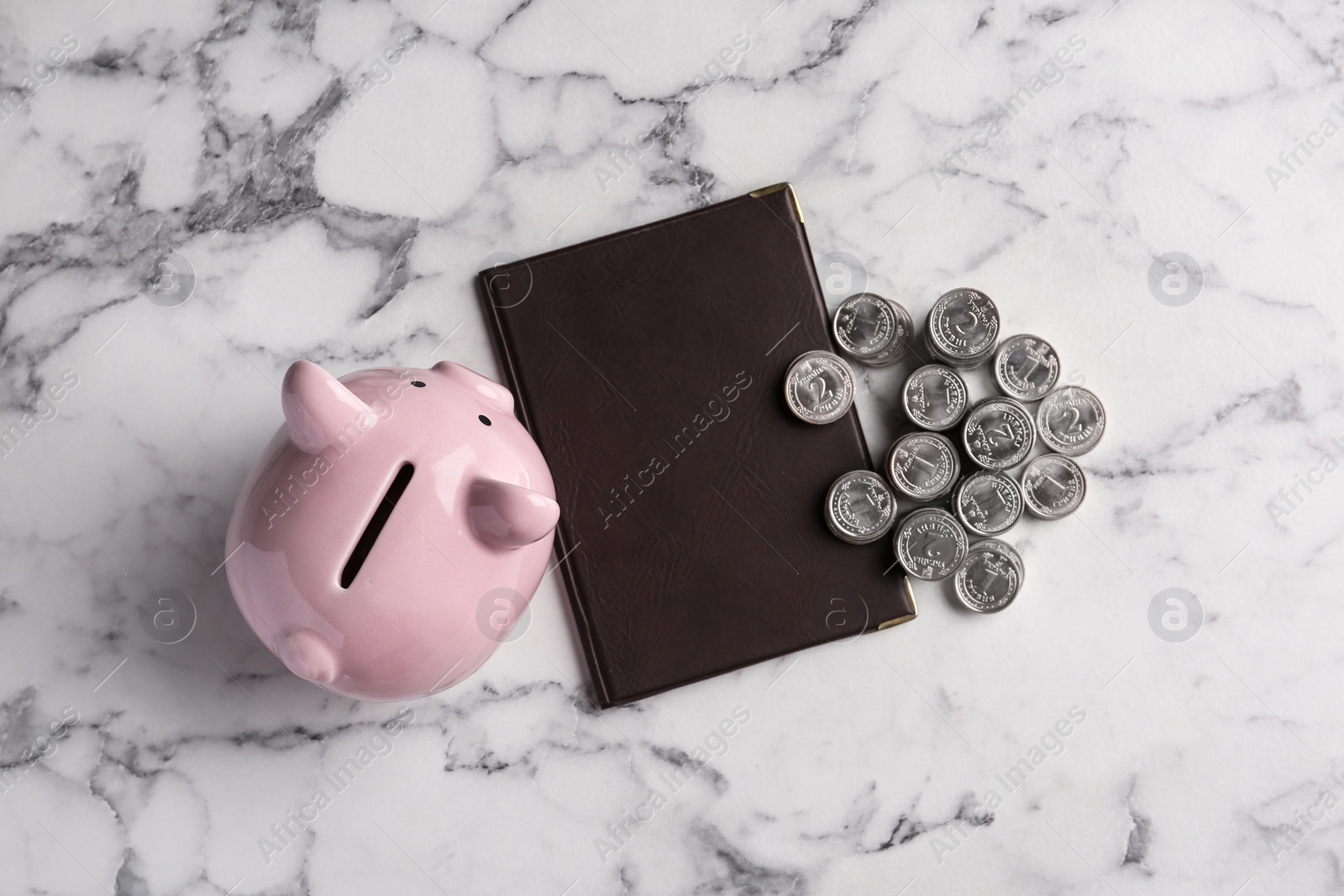 Photo of Pension certificate with Ukrainian coins and piggybank on marble background, top view