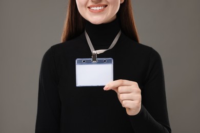 Woman with blank badge on grey background, closeup