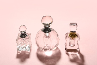 Photo of Different elegant perfume bottles on pink background