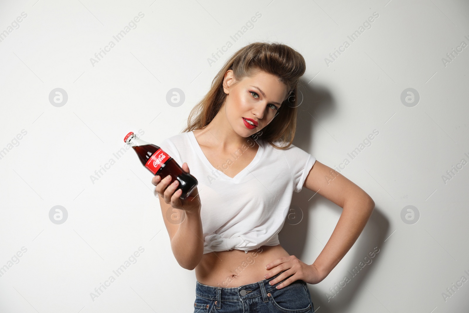 Photo of MYKOLAIV, UKRAINE - NOVEMBER 28, 2018: Young woman with bottle of Coca-Cola on white background