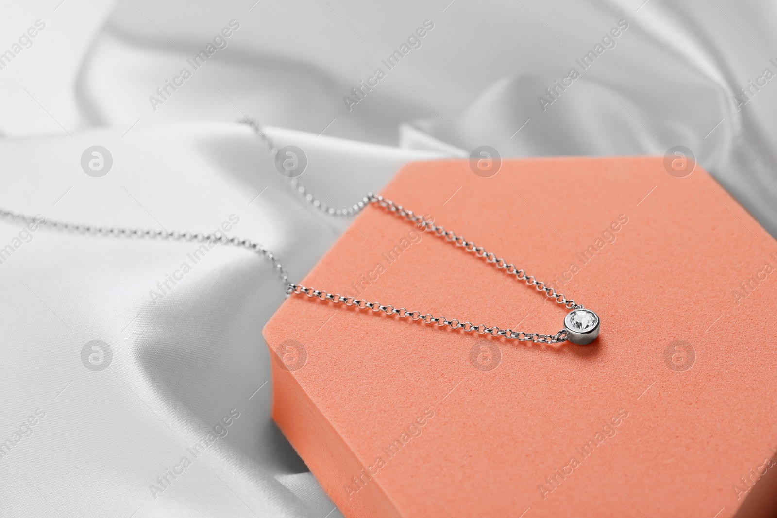 Photo of Beautiful necklace with gemstone on orange podium. Luxury jewelry
