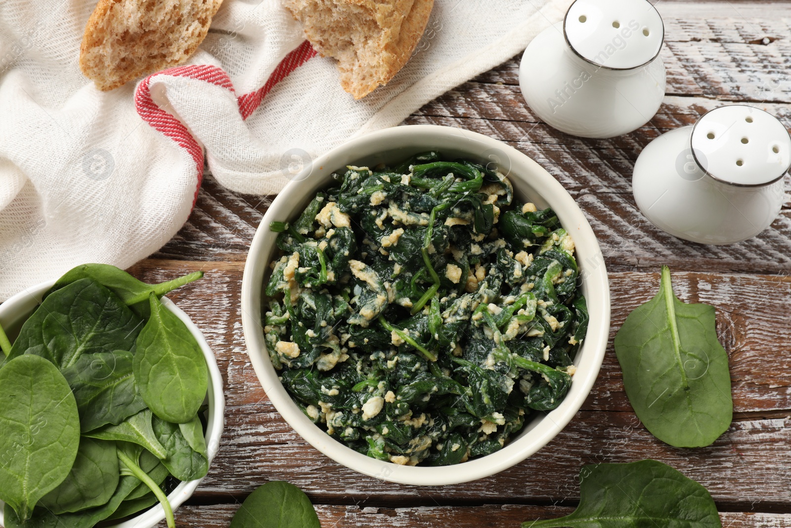 Photo of Tasty spinach dip with eggs in bowl and bread on wooden table, flat lay