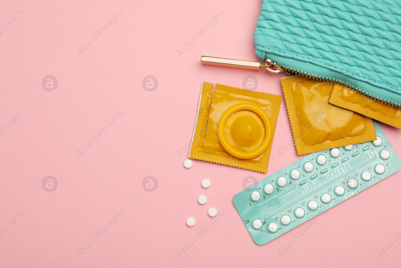 Photo of Condoms and birth control pills in purse on pink background, top view with space for text. Safe sex