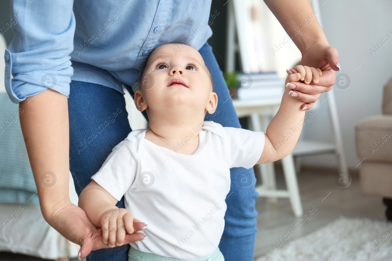 Photo of Baby taking first steps with mother's help at home