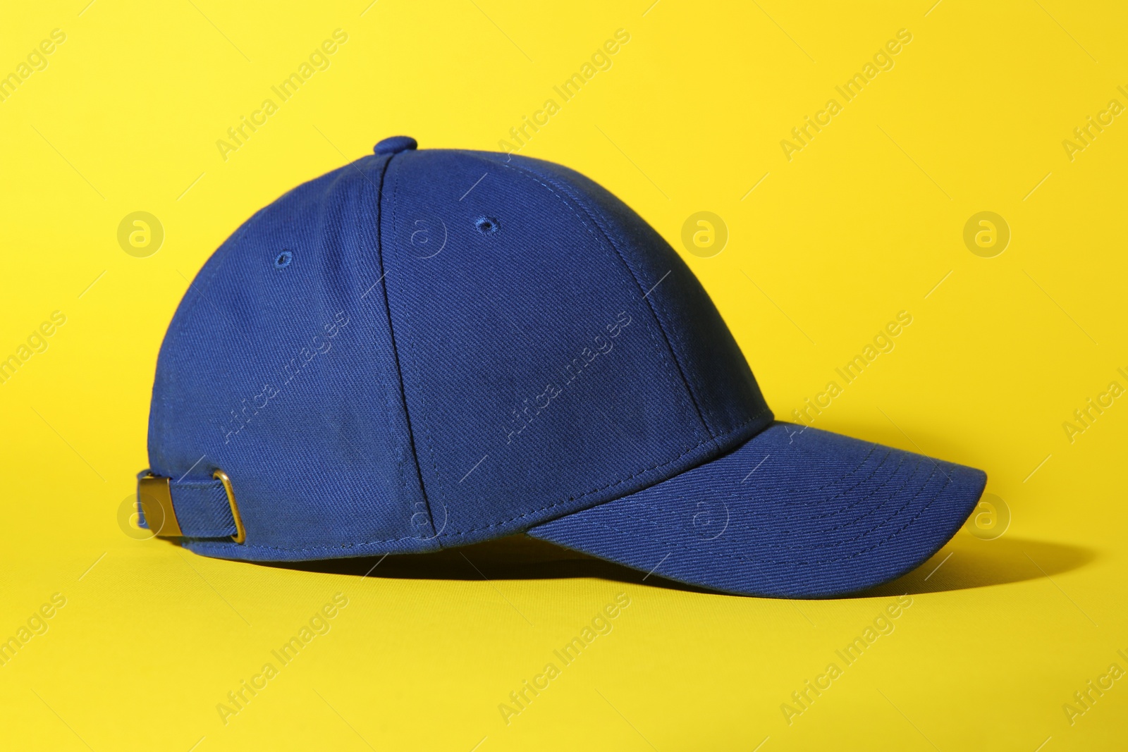 Photo of Stylish blue baseball cap on yellow background