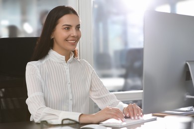 Photo of Happy woman using modern computer at desk in office