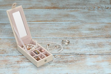 Jewelry box with many different accessories on rustic wooden table. Space for text