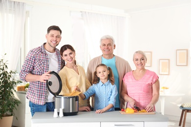 Photo of Happy family preparing food with modern multi cooker in kitchen