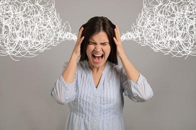 Stressed and upset young woman on grey background