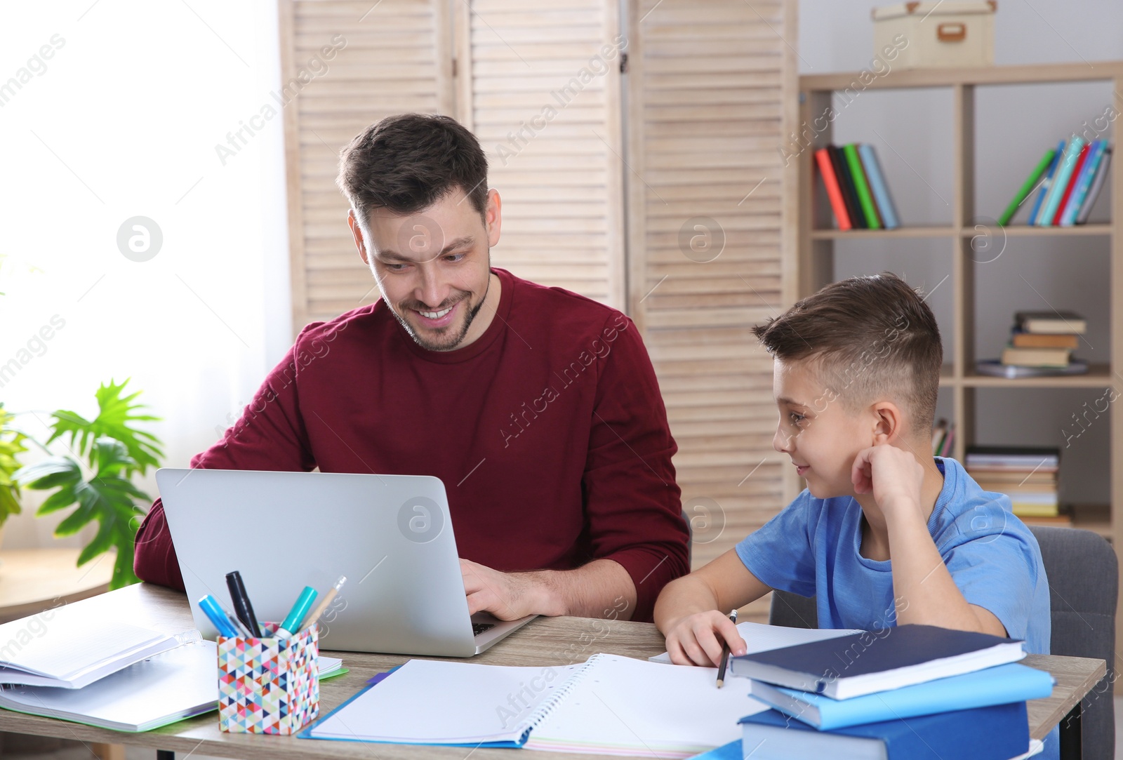 Photo of Dad helping his son with homework in room