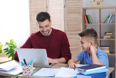 Dad helping his son with homework in room